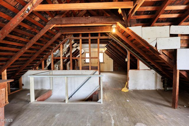 a view of an empty room with wooden floor and stairs