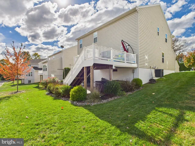 a view of a white house next to a yard with big trees