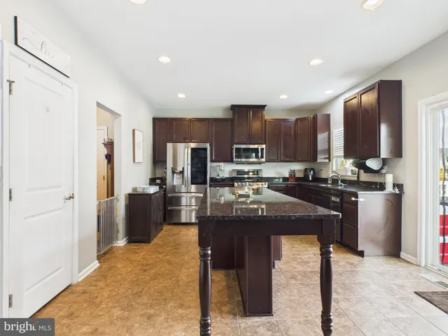 a kitchen with stainless steel appliances granite countertop a refrigerator a stove a sink a dining table and chairs