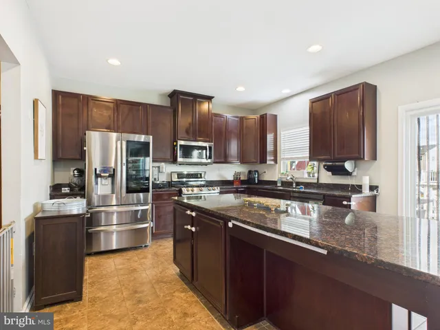 a kitchen with stainless steel appliances granite countertop a refrigerator a stove top oven a sink and dishwasher