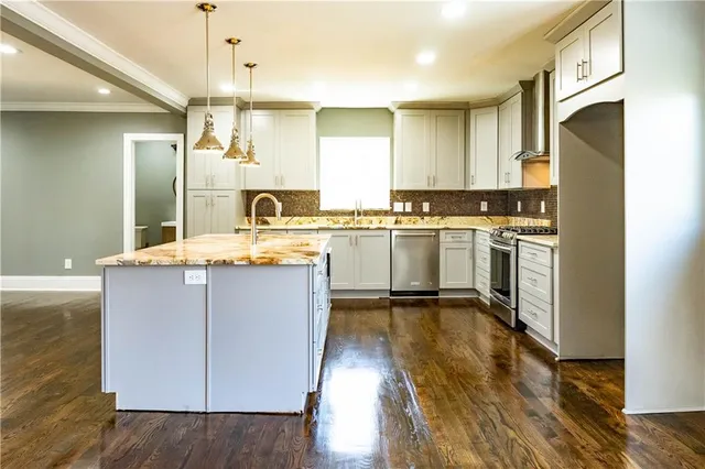 a kitchen with kitchen island granite countertop a sink cabinets and refrigerator