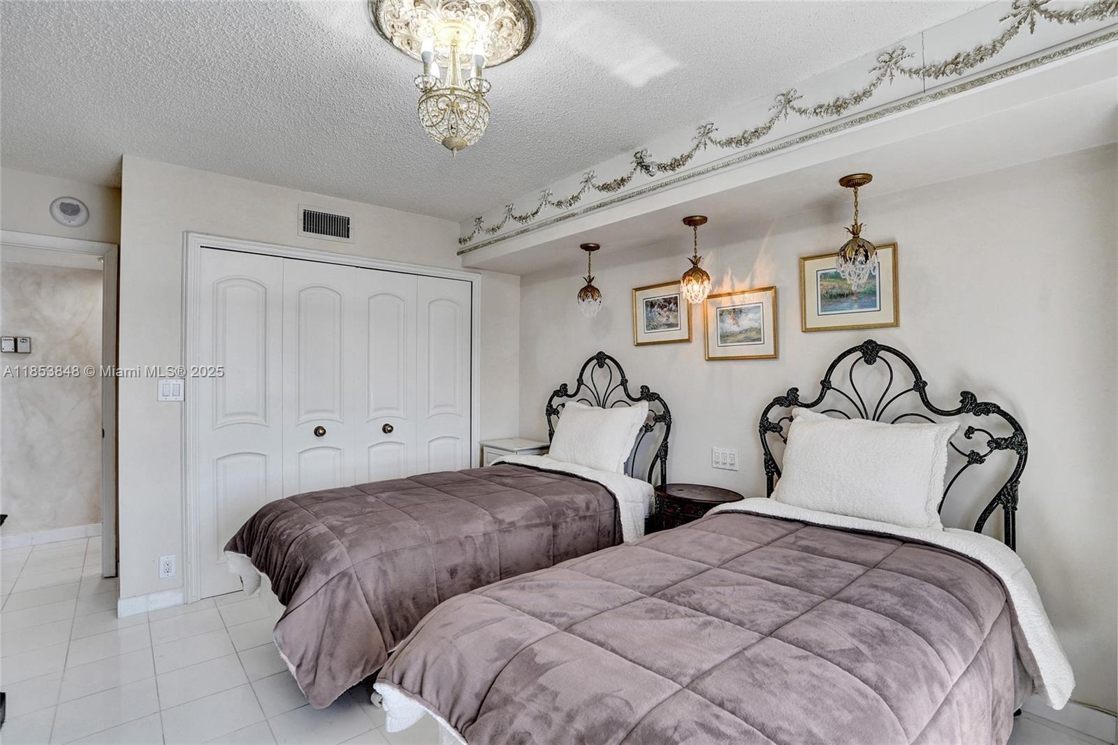 3530 Mystic Pointe Drive, Unit 2915 Aventura, FL 33180 - Photo 18 of 41 a bedroom with two beds and a chandelier