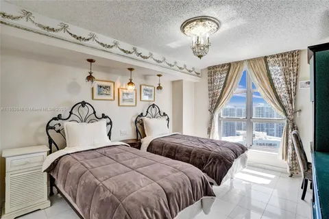 a bedroom with two large bed and a chandelier