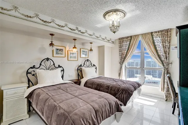 a bedroom with two large bed and a chandelier