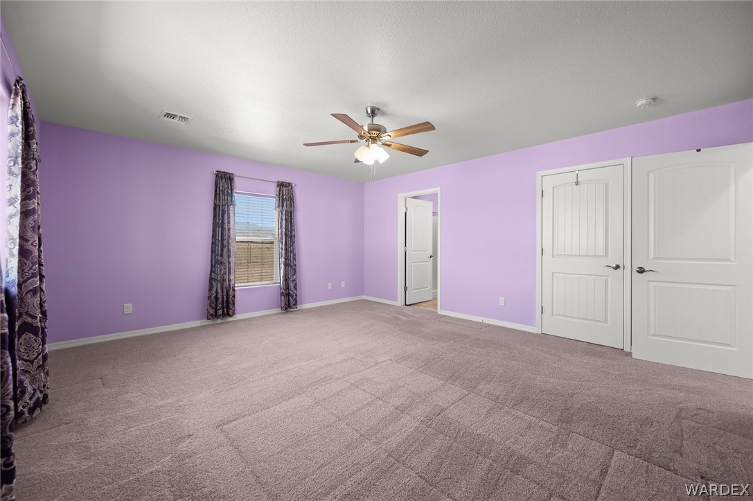 3411 West Carmichael Road Golden Valley, AZ 86413 - Photo 5 of 97 Unfurnished bedroom featuring a ceiling fan, carpet floors, and a closet