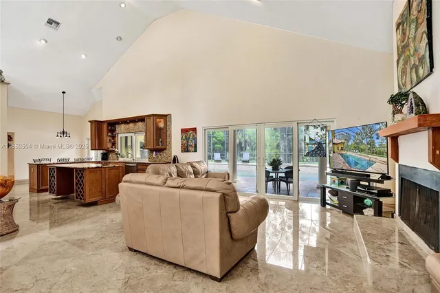 a kitchen with stainless steel appliances granite countertop a sink dishwasher a stove a refrigerator a dining table and chairs with wooden floor