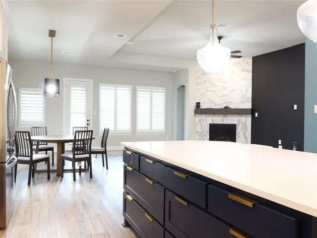 a kitchen with a stove a refrigerator dining table and chairs with wooden floor