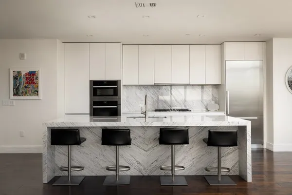 a large kitchen with kitchen island granite countertop a table chairs in it and wooden floors