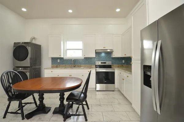 a kitchen with kitchen island a dining table chairs and a refrigerator