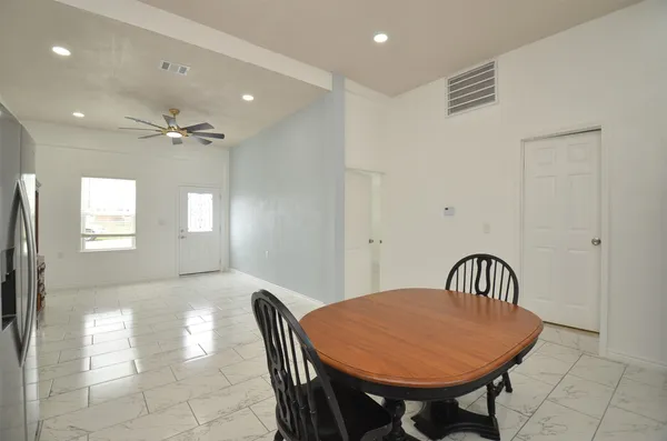 a kitchen with stainless steel appliances granite countertop a dining table chairs refrigerator and sink