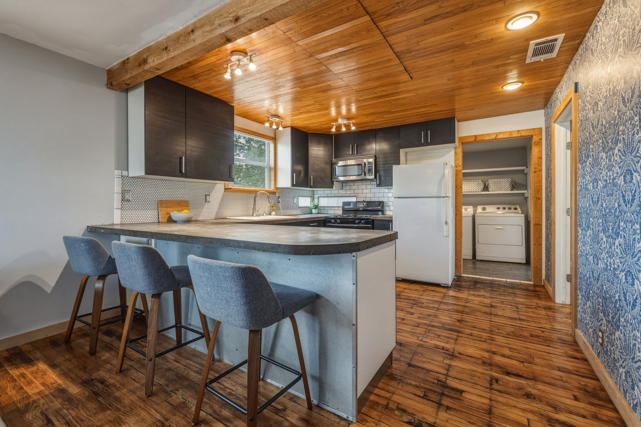 4806 Santa Anna Street Austin, TX 78721 - Photo 6 of 35 a kitchen with stainless steel appliances kitchen island granite countertop a table chairs in it and wooden floors