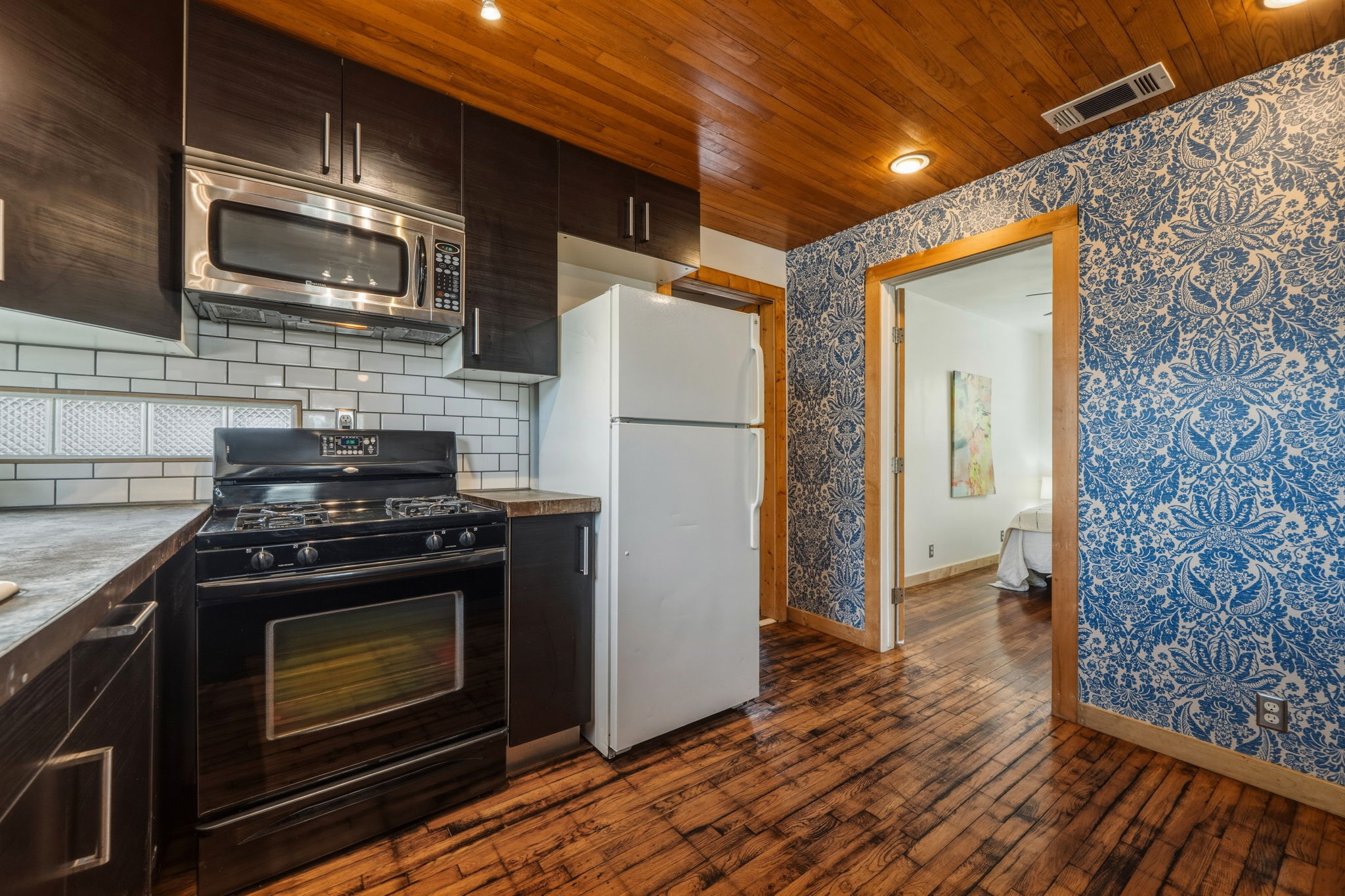 4806 Santa Anna Street Austin, TX 78721 - Photo 10 of 35 Kitchen featuring concrete counters, gas stove, microwave, freestanding refrigerator, and wood flooring & ceiling