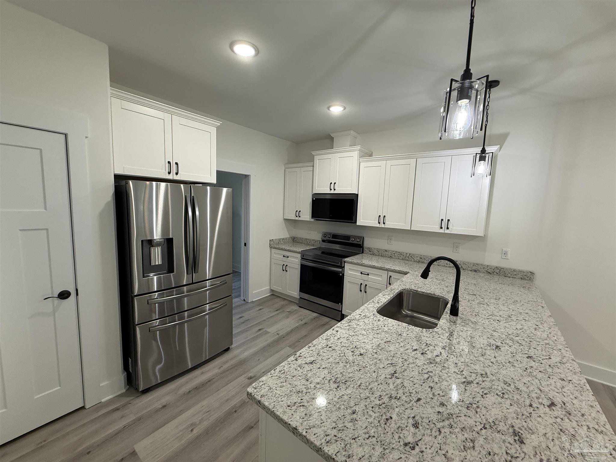 8636 Messick Street, Unit A Pensacola, FL 32534 - Photo 3 of 13 a kitchen with granite countertop a refrigerator a sink a stove a microwave and island