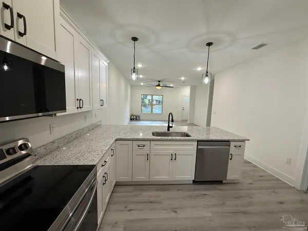 a kitchen with stainless steel appliances granite countertop a sink a stove and a wooden floor