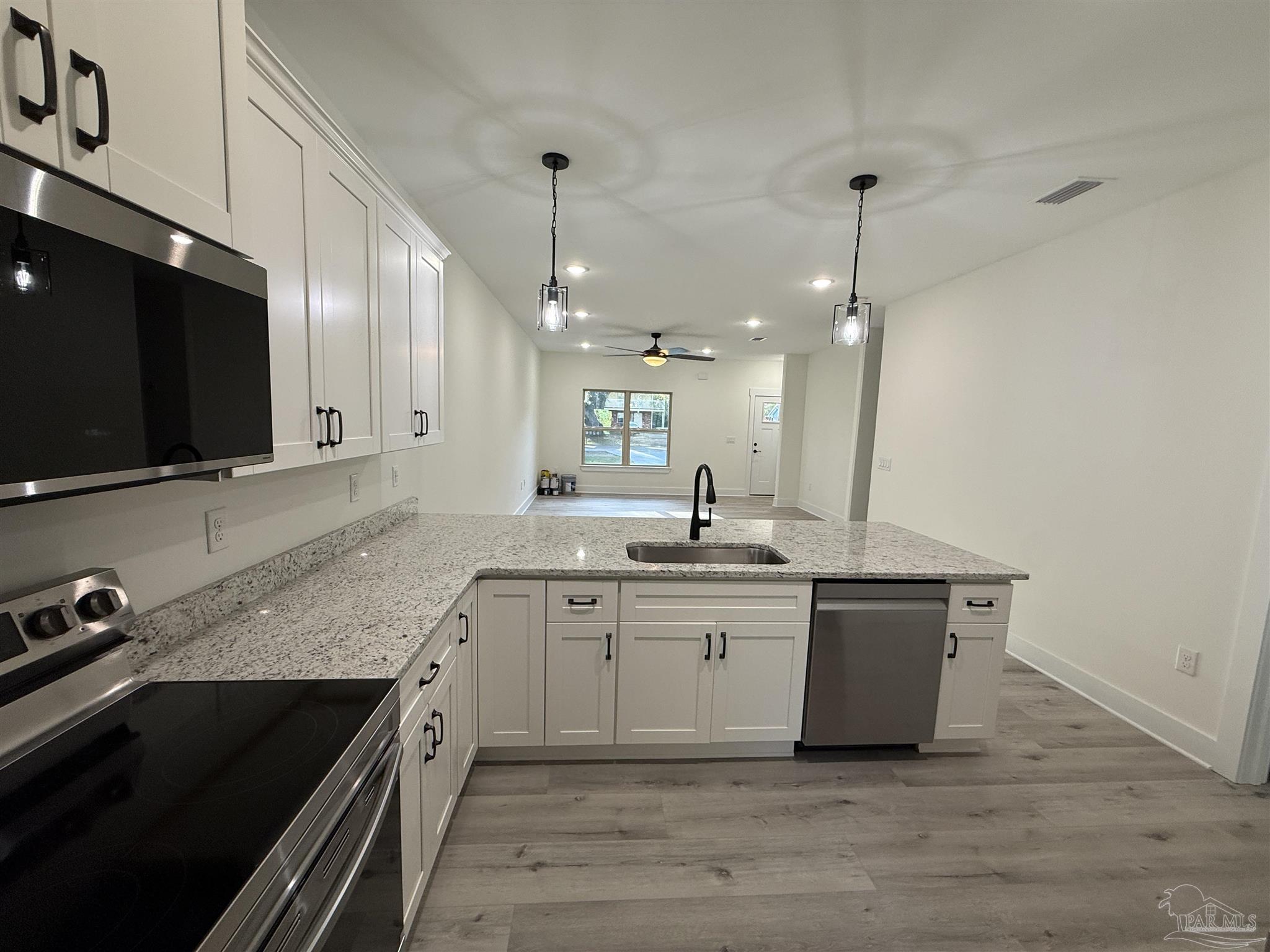 8636 Messick Street, Unit A Pensacola, FL 32534 - Photo 4 of 13 a kitchen with stainless steel appliances granite countertop a sink a stove and a wooden floor