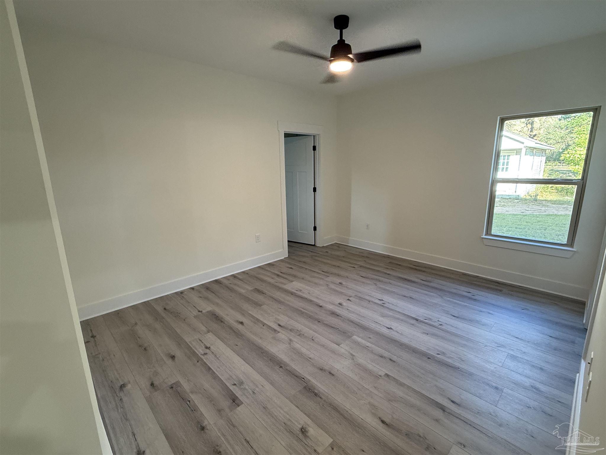 8636 Messick Street, Unit A Pensacola, FL 32534 - Photo 7 of 13 an empty room with wooden floor chandelier fan and windows