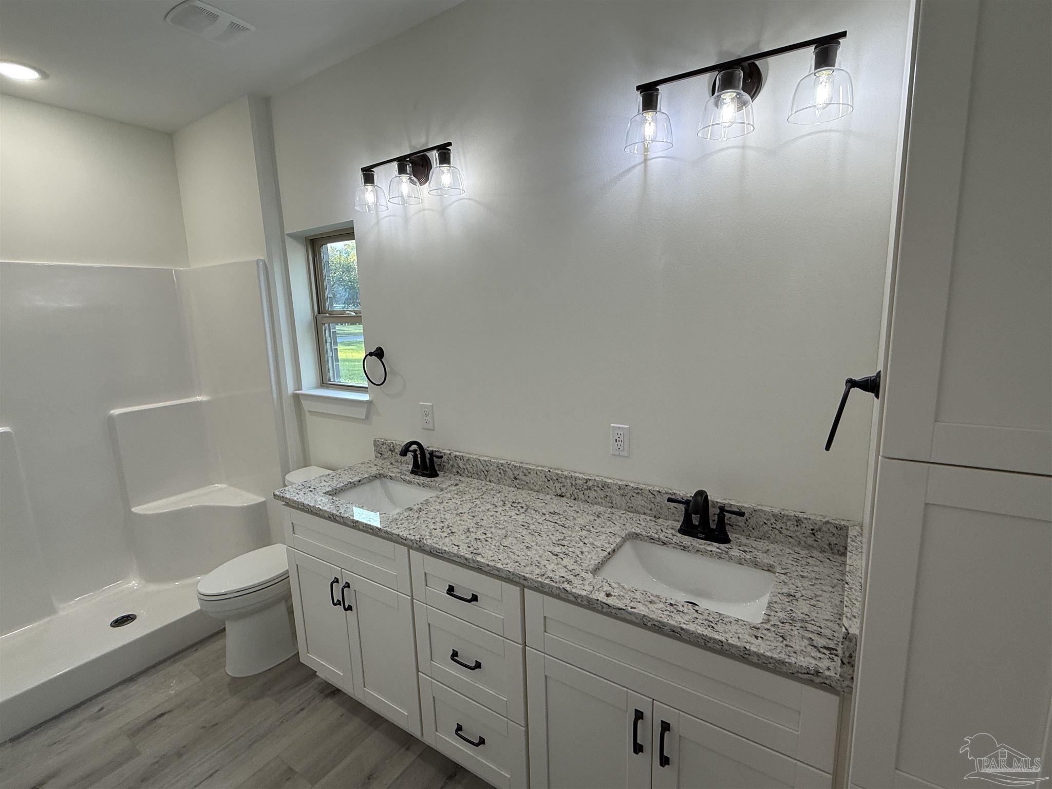 8636 Messick Street, Unit A Pensacola, FL 32534 - Photo 9 of 13 a bathroom with a granite countertop sink a toilet and mirror