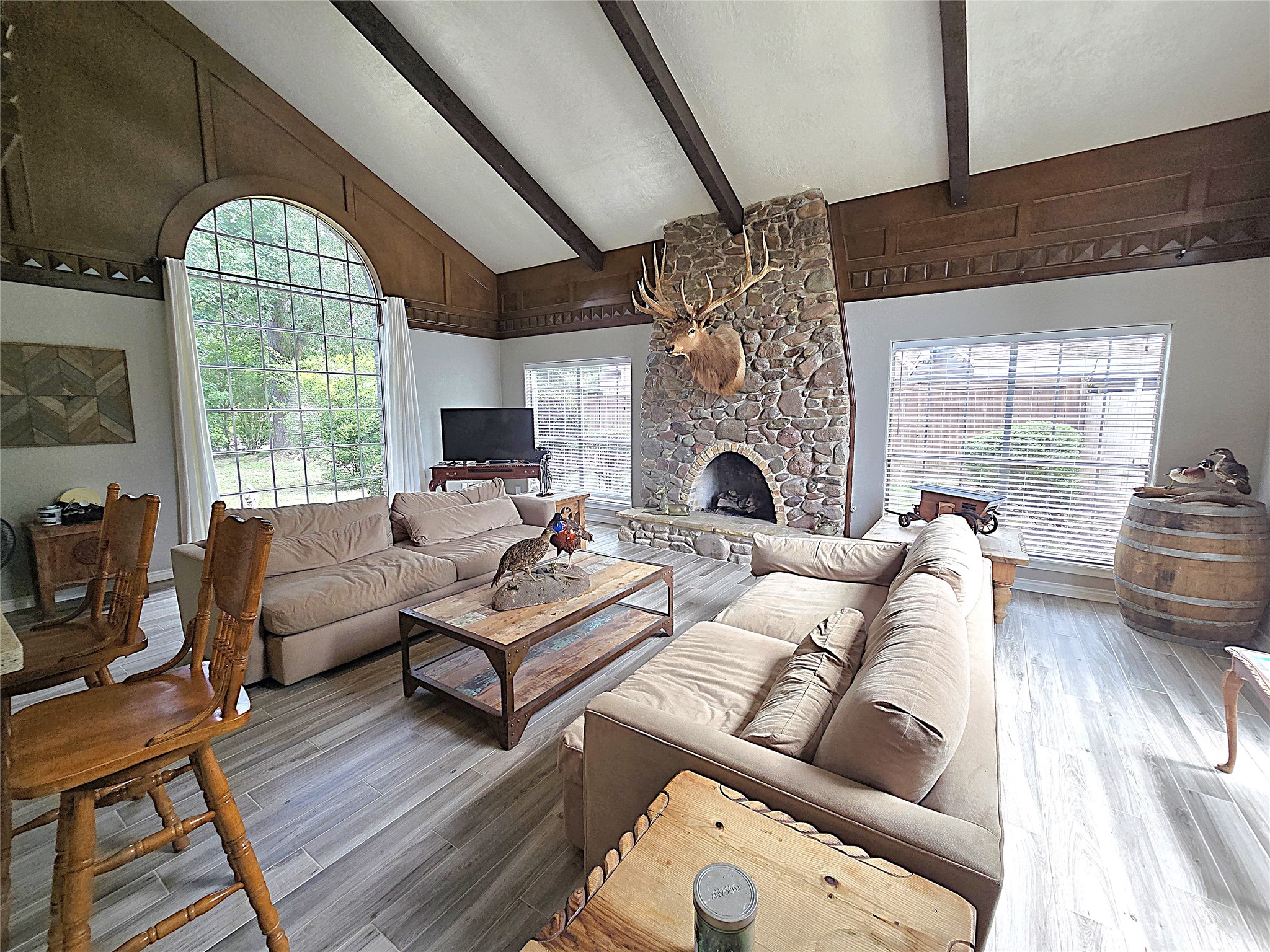 560 Brandon Road Conroe, TX 77302 - Photo 34 of 45 Spacious living room featuring vaulted ceilings, a stunning stone fireplace, and large windows that flood the space with natural light. Perfect for cozy gatherings and relaxation.