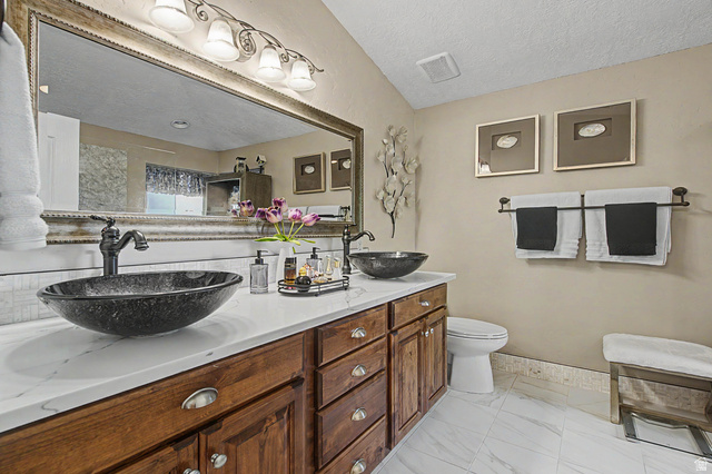 3034 Swiss Drive Santa Clara, UT 84765 - Photo 45 of 59 Dual vessel sinks with bronze-finish fixtures set on a white countertop, complemented by a wood-finish vanity with ample storage