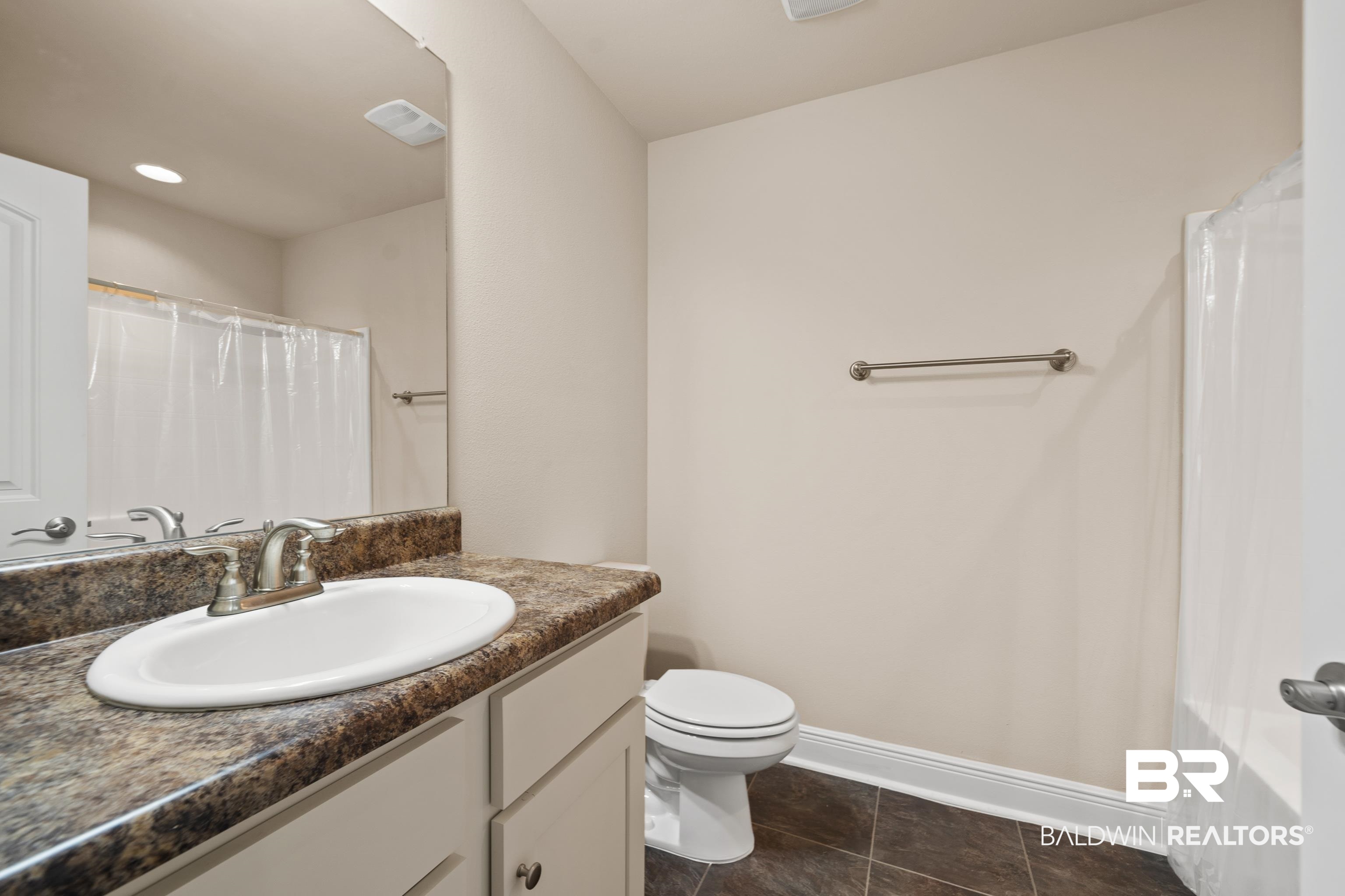22631 Lake South Drive Foley, AL 36535 - Photo 16 of 25 Bathroom featuring tile patterned floors, curtained shower, vanity, and toilet