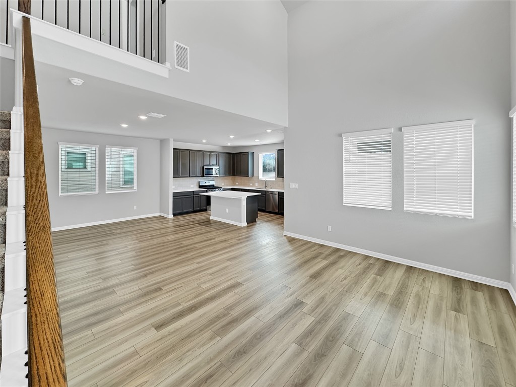 2437 Roosevelt Road Leander, TX 78641 - Photo 15 of 35 Unfurnished living room with a high ceiling, stairway, and light wood finished floors