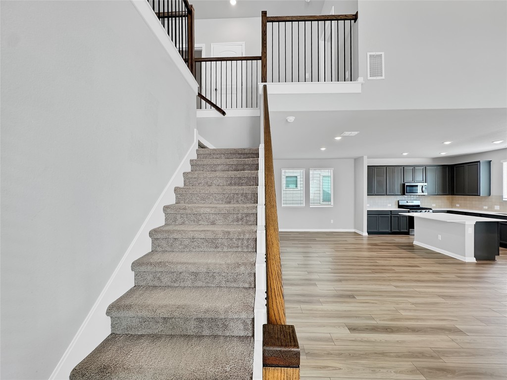 2437 Roosevelt Road Leander, TX 78641 - Photo 19 of 35 Stairs with recessed lighting, wood finished floors, and a towering ceiling