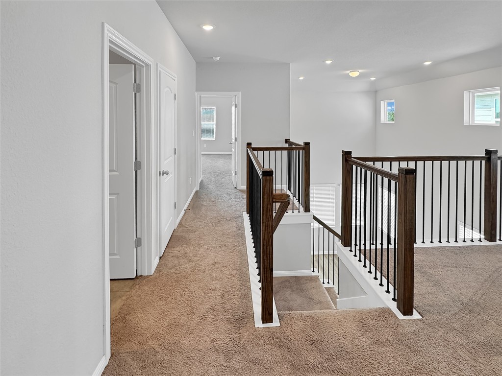 2437 Roosevelt Road Leander, TX 78641 - Photo 26 of 35 Corridor featuring light colored carpet, an upstairs landing, and recessed lighting. Looking to the hallway with laundry room and Primary suite at the end.
