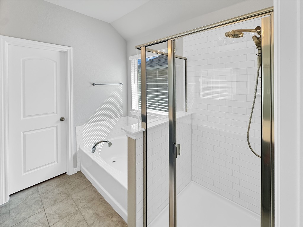 2437 Roosevelt Road Leander, TX 78641 - Photo 32 of 35 Bathroom with a bath, a shower stall, lofted ceiling, and light tile patterned floors