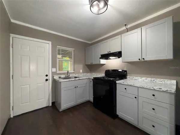 a kitchen with granite countertop white cabinets and black appliances