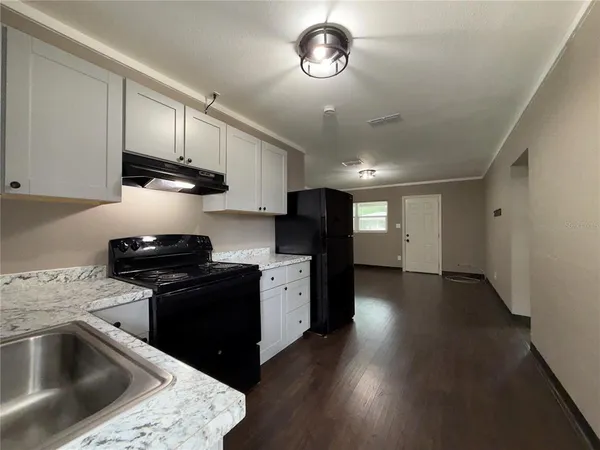 a kitchen with stainless steel appliances granite countertop a sink dishwasher a stove and a refrigerator with wooden floor