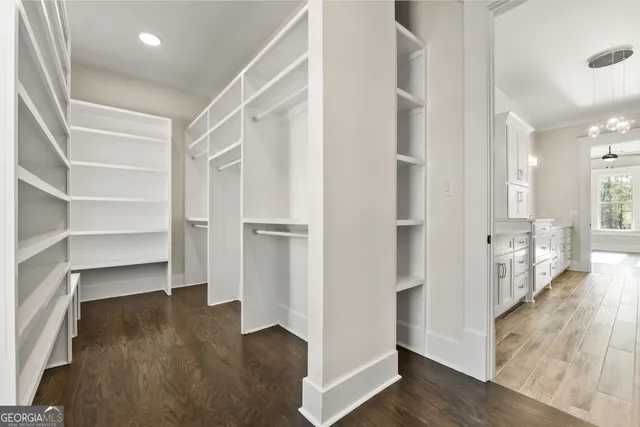 an empty room with chandelier fan and windows