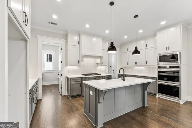 a open kitchen with stainless steel appliances granite countertop a stove refrigerator and a oven with wooden floor