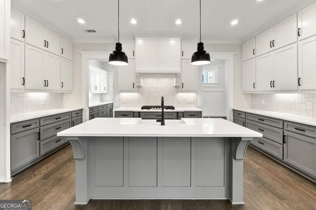 a kitchen with kitchen island a sink stainless steel appliances and white cabinets