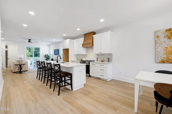 a kitchen with a dining table chairs and white appliances with wooden floor