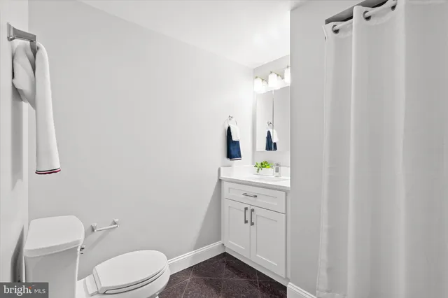 a bathroom with a granite countertop sink toilet and mirror