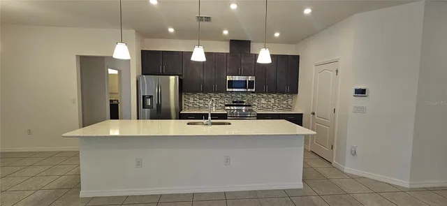 a large kitchen with kitchen island a counter top stainless steel appliances and cabinets