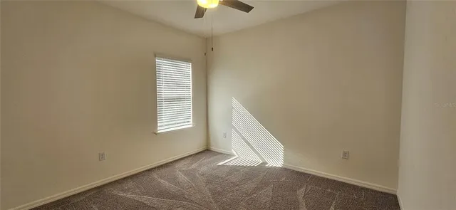 an empty room with windows and chandelier fan