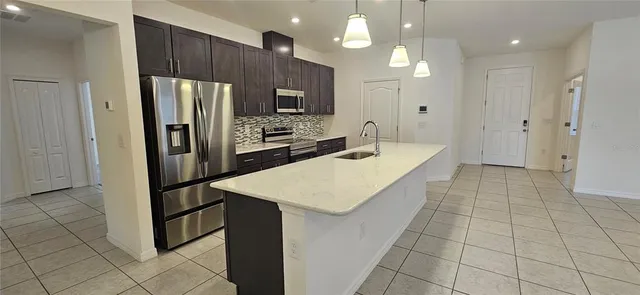 a large kitchen with stainless steel appliances a refrigerator and a counter space