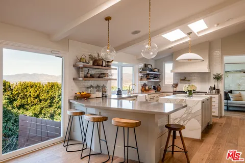 a kitchen with stainless steel appliances granite countertop a stove a refrigerator a oven a sink with island chairs and wooden floor