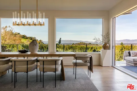a dining table with chairs and view of living room