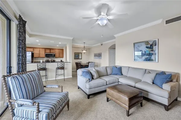 a living room with furniture kitchen view and a chandelier