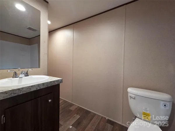 a bathroom with a granite countertop sink toilet and a mirror