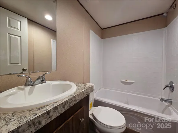 a bathroom with a granite countertop sink a toilet and shower