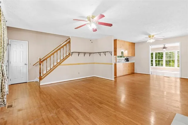 a view of an empty room with window and wooden floor