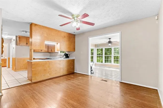 a large white kitchen with wooden floor and a window