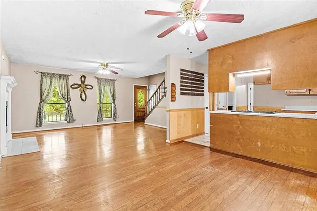 a view of a room with kitchen island stainless steel appliances wooden floor and window