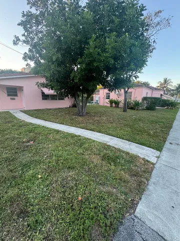a view of a house with a big yard and large trees