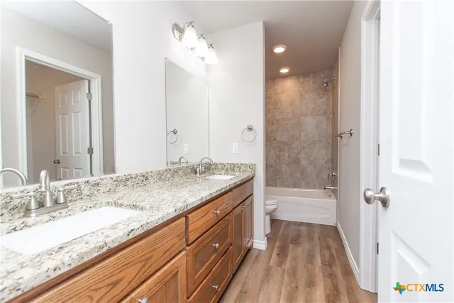 a bathroom with a granite countertop sink a toilet and shower