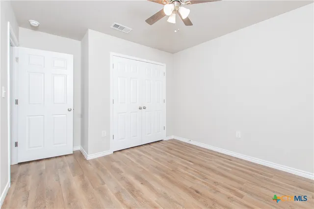 an empty room with a hardwood and ceiling fan