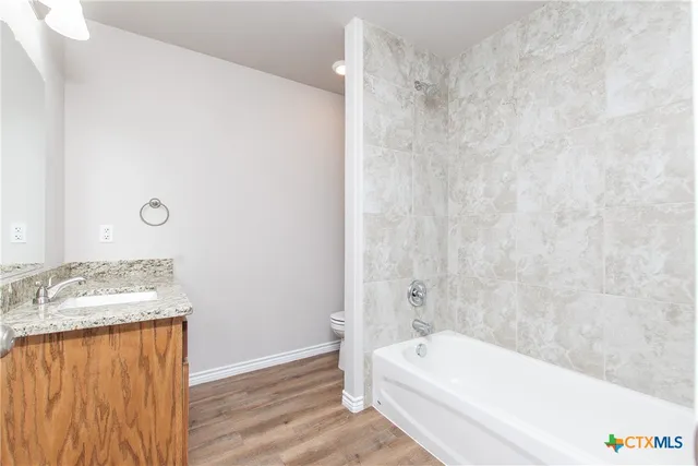 a bathroom with a granite countertop sink and a bathtub